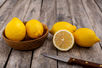 Fresh ripe lemons and knife on wooden background