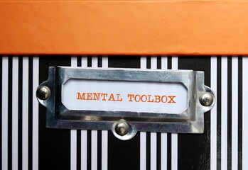 Orange box with tag written MENTAL TOOLBOX, refers to various tools to tackle different difficult situations, mental tools people use to enhance their self improvement