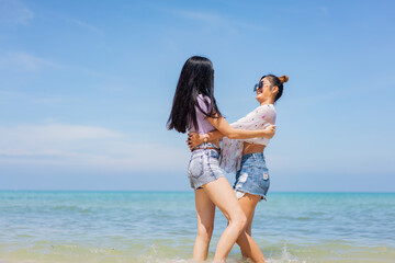 Two girlfriends hugging up and enjoying on the sea beach. A pair of girls in love cuddling on a tropical beach. romantic young lesbian couples in love and walking together on the beach.Concept of LGBT