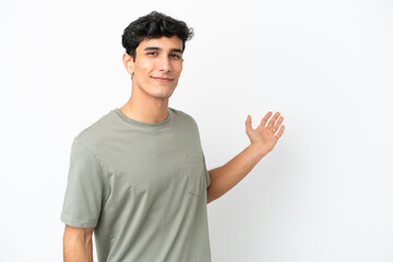 Fototapeta premium Young Argentinian man isolated on white background extending hands to the side for inviting to come