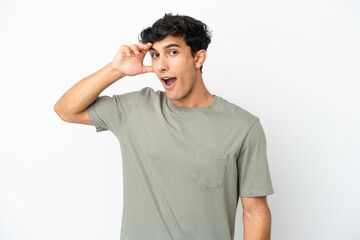 Young Argentinian man isolated on white background doing surprise gesture while looking to the side