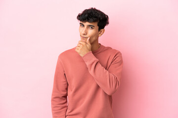 Young Argentinian man isolated on pink background having doubts