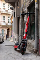 Scooter sharing. A red sharing scooter stands beside the wall of an old house. Scooter on the street of Istanbul.