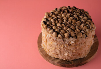 photo tall walnut cake on a wooden board on a pink background