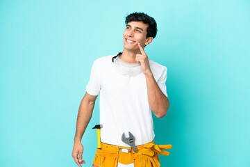 Young electrician Argentinian man isolated on blue background thinking an idea while looking up