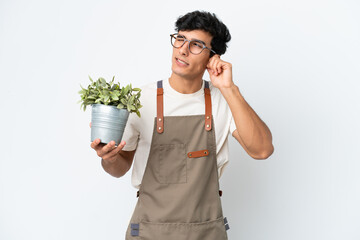 Gardener Argentinian man holding a plant isolated on white background frustrated and covering ears