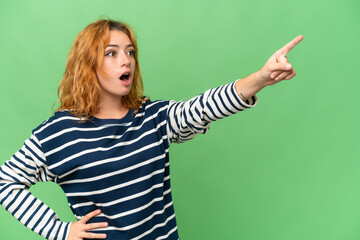 Young caucasian woman isolated on green screen chroma key background pointing away