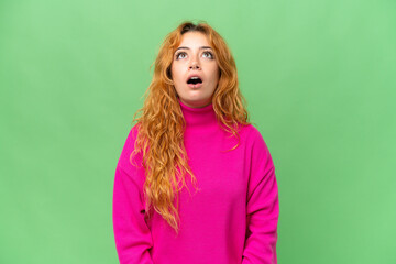 Young caucasian woman isolated on green screen chroma key background looking up and with surprised expression