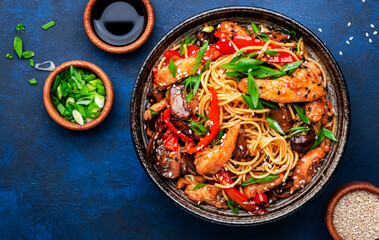 Stir fry noodles with chicken, red paprika, mushrooms, chives and sesame seeds in bowl. Asian...