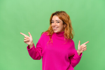 Young caucasian woman isolated on green screen chroma key background pointing finger to the laterals and happy