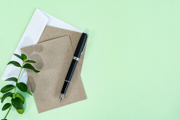 Business concept. Paper rustic sheet, envelope and pen on green background.