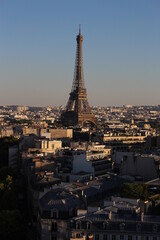 Naklejka premium Eiffel tower at golden hour seen among the built up urban Parisian environment. Modern travel background, French concept