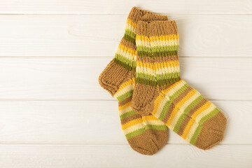 Bright handmade socks on a white wooden background.Knitted warm, winter socks. Wool yarn. winter hobbies. Hobby.Place for text, space for copy.