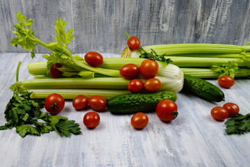 Ingredients for a vitamin salad, the parsley, the cherry tomatoes, the cucumbers and the stalks of the celery are on a wooden table