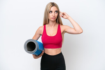 Young sport blonde woman going to yoga classes while holding a mat isolated on white background having doubts and thinking