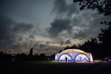 Naklejka na ściany i meble Large wedding tent in the open area for receiving guests. Evening photo with a beautiful sunset
