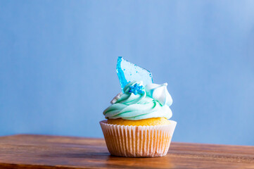 Homemade cupcake of blue color placed on wooden desk. Winter and christmas theme, snowflakes on...