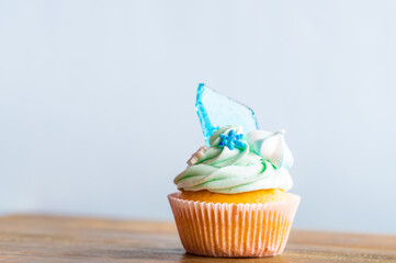 Homemade cupcake of blue color placed on wooden desk. Winter and christmas theme, snowflakes on...