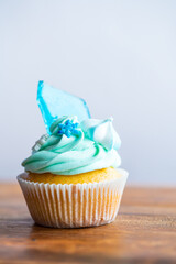 Homemade cupcake of blue color placed on wooden desk. Winter and christmas theme, snowflakes on...