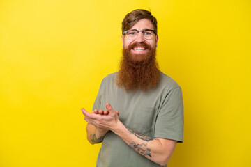 Redhead man with beard isolated on yellow background applauding