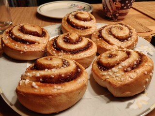 Closeup of a delicious homemade Cinnamon roll buns on white plate on wooden table