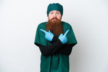 Surgeon redhead man in green uniform isolated on white background pointing to the laterals having doubts