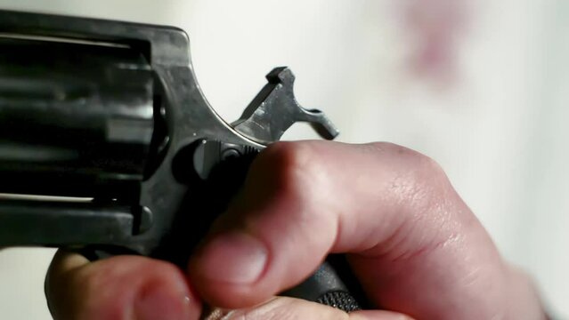 Close-up of a person holding and aiming a black color revolver gun