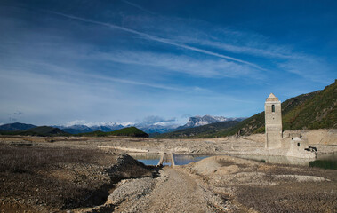 The reservoir with the tower of the church of the Assumption emerged due to drought and lack of rainfall.  Climate change. Autumn 2022. Huesca, Spain.