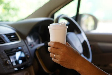 Closeup hand hold paper cup of coffee to drink in car. Concept, baverge for refreshing or helping to awake from asleep during driving that can cause car accident.  
