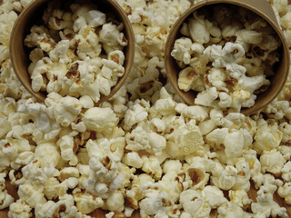 Paper cups with popcorn lie on a pile of popcorn, background