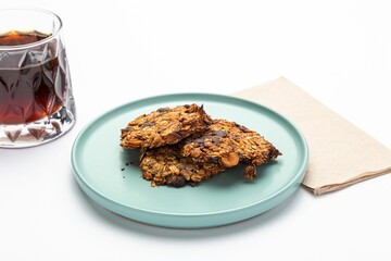 Isolated shot of a plate of oatmeal treats and a glass of drink on a white background