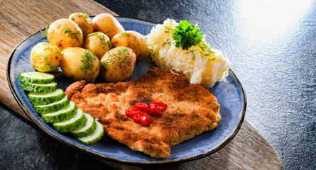 Pork cutlet coated with breadcrumbs with potatoes and cabbage