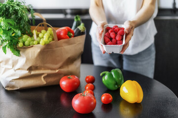 woman unpacking grocery bag at kitchen, cropped shot