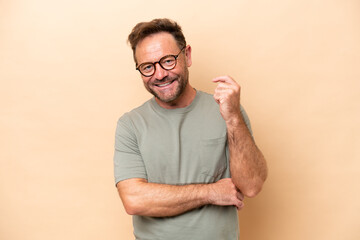 Middle age caucasian man isolated on beige background laughing