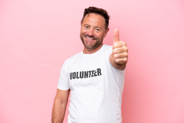 Middle age volunteer man isolated on pink background isolated on pink background with thumbs up because something good has happened