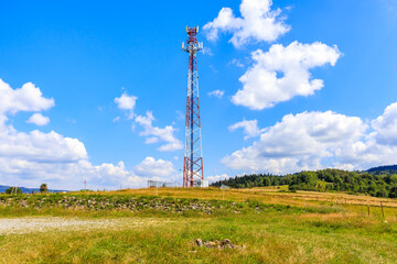 Cellphone tower on green meadow with flowers in Beskidy Mountains on sunny summer day near Zywiec, Poland - 549449766