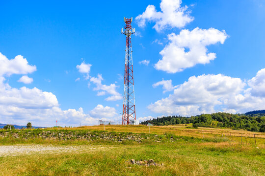 Cellphone tower on green meadow with flowers in Beskidy Mountains on sunny summer day near Zywiec, Poland - Powered by Adobe