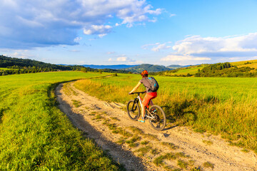 Woman riding mountain bike on dirt road in Beskidy Mountains near Zywiec, Poland