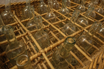 Dark empty wine bottles standing in wicker basket in rows in compartments from above