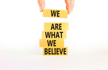 We are what we believe symbol. Concept words We are what we believe on wooden blocks. Businessman hand. Beautiful white background. Business, motivational we are what we believe concept. Copy space.