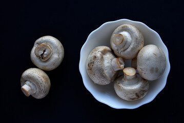 Porcini mushrooms in a white plate on a black background. Fruits of large white champignons close-up. Beautiful mushrooms in a plate.