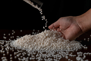 Close-up of plastic polymer granules, hand hold Polymer pellet, polymer plastic, compound polymer,...