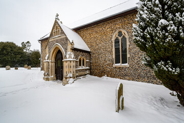All Saints church in the small village of Sutton in the British countryside, it is totally covered in deep snow during a rare snow storm in the UK
