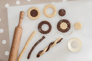 A rolling pin, a cookie cutter, a cutting board with a raw sand dough.