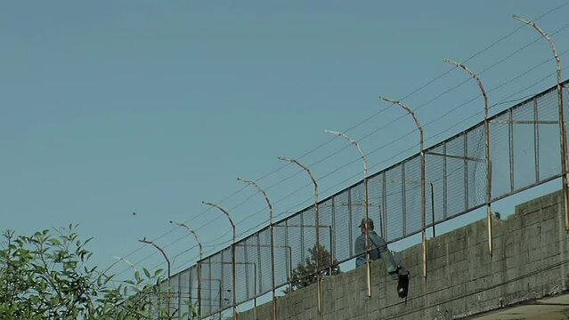 Prison Officer walking Along an Outdoor Walkway in an Old Prison in Latin America. 4K Resolution.