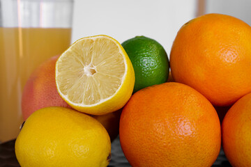 Citrus fruits oranges grapefruit lemon lime in the kitchen with an orange juice ready to eat and...