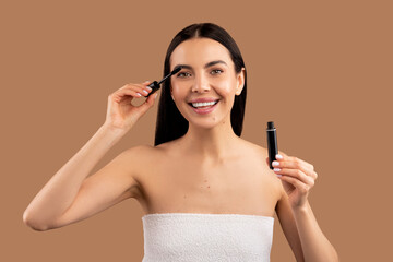 Fototapeta premium Beautiful young woman applying mascara on her eyelashes