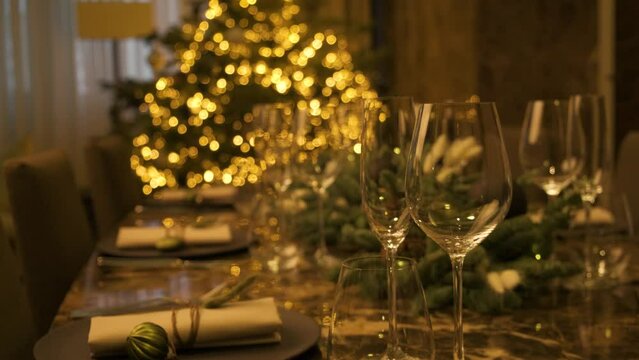 Traditionally decorated christmas table for a winter holidays with a christmas tree in the background.