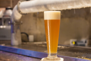 glass of cold and creamy beer on the counter of a lighted bar