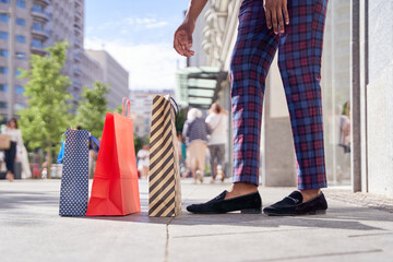 fashionable African man picking up shopping bags from the floor